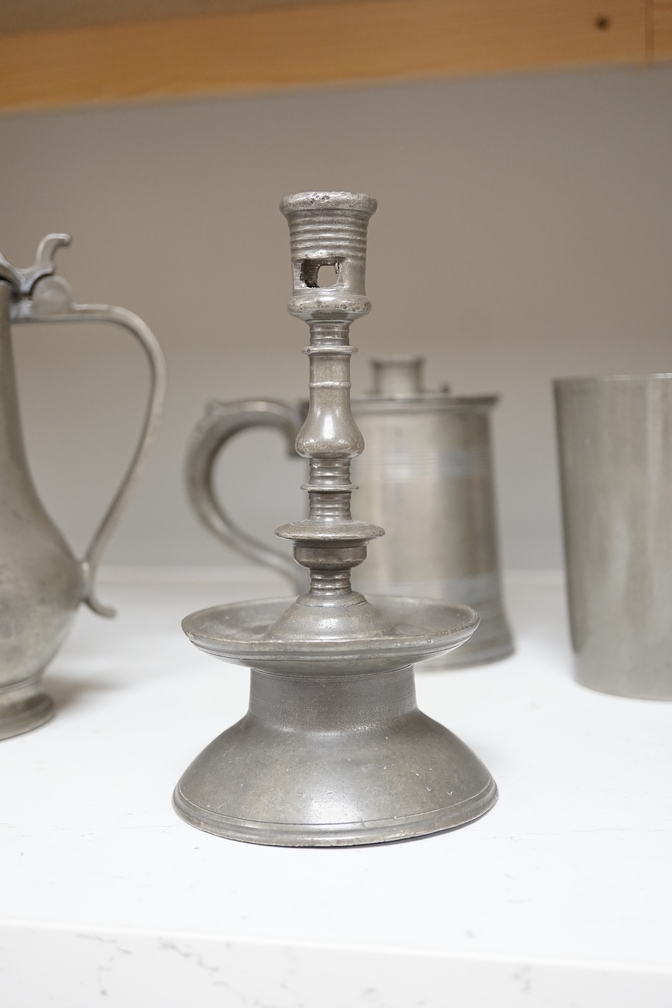 Six items of 18th century and later pewter including a jug, candlesticks, a pint measure, and a bronze hand bell, 24cm high. Condition - fair.